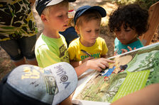 Kinder an einer Karte im Wald.