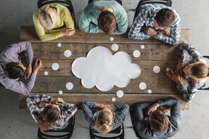 Menschen sitzen an einem Tisch und tauschen sich aus © AdobeStock