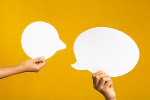 Hände die Sprechblasen hochhalten auf gelbem Hintergrund &copy; AdobeStock meeboonstudio